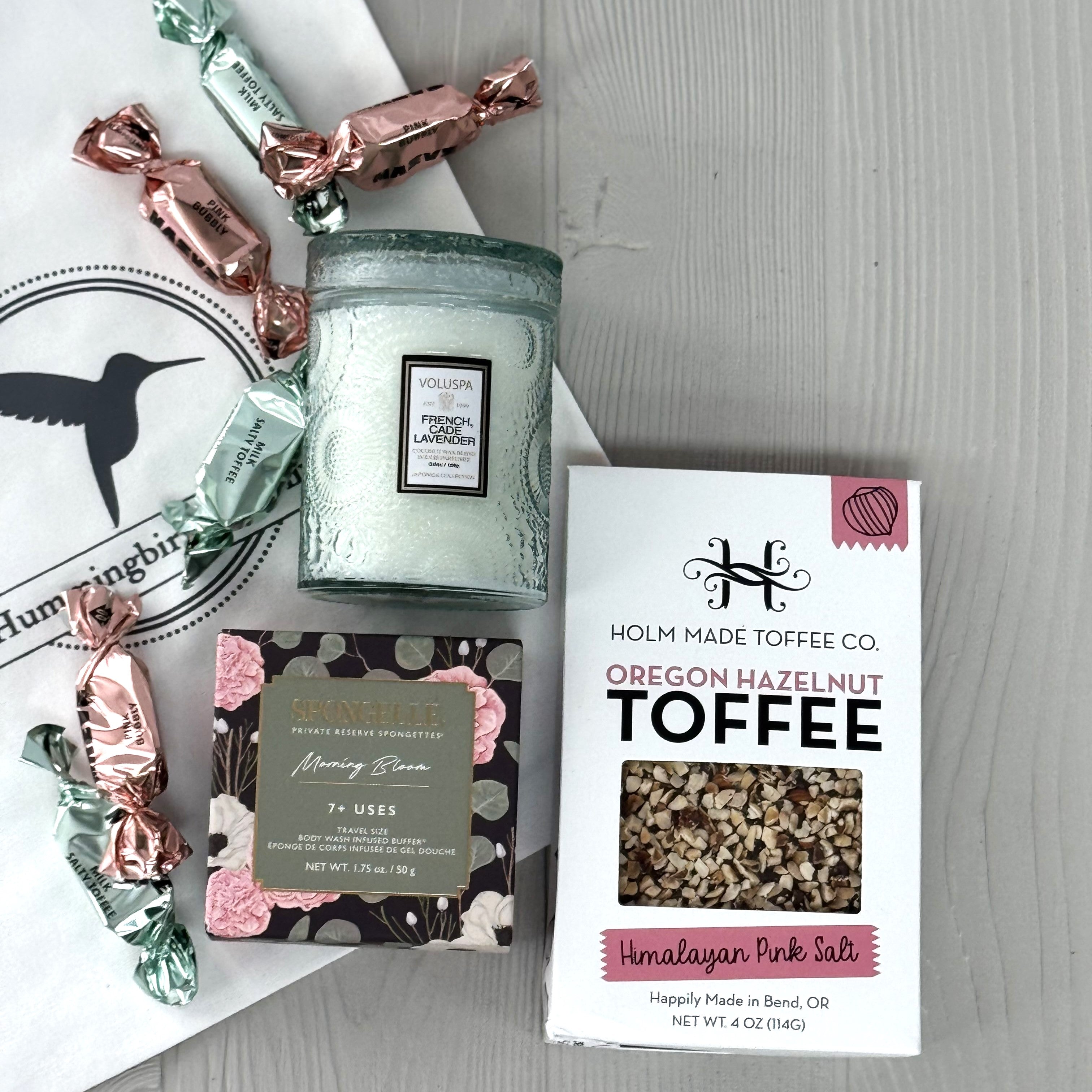 gift basket includes a scented candle, toffee, chocolate, soap,