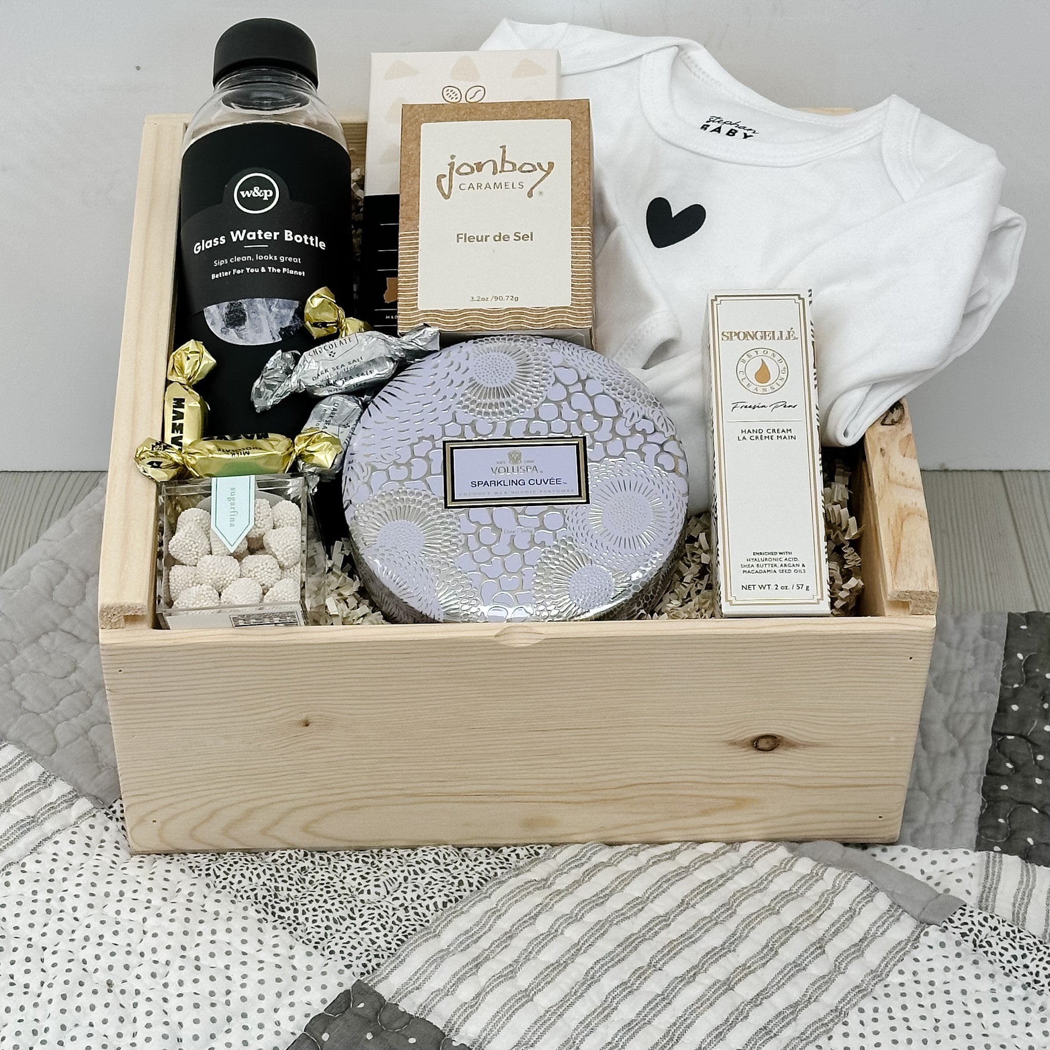 water bottle, baby gown, chocolate, caramel, hand cream, candy, candle, baby quilt all included in our mom & baby gift basket.