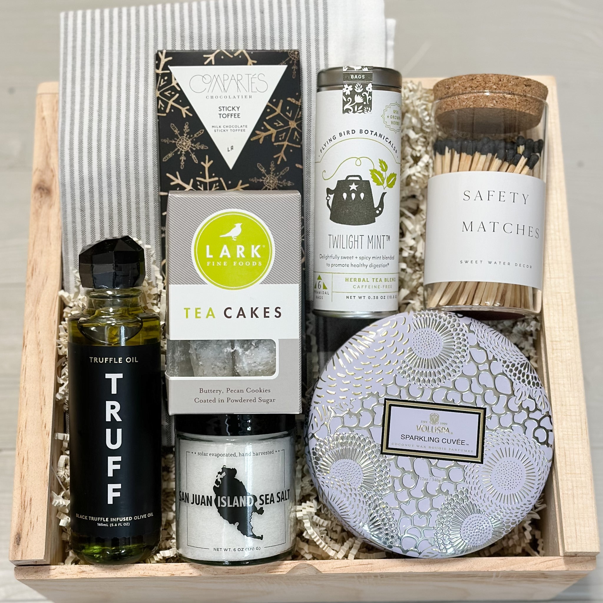 home sweet home gift basket includes truffle oil, salt, candle, matches, chocolate, tea, cookies, dish towel