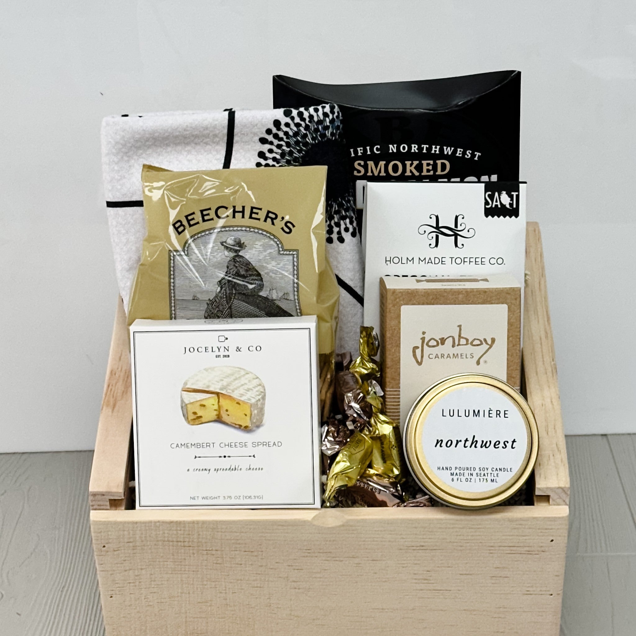 dish towel, smoked salmon, beechers crackers, toffee, caramel, cheese, truffles, northwest candle all part of our pnw charcuterie gift basket.