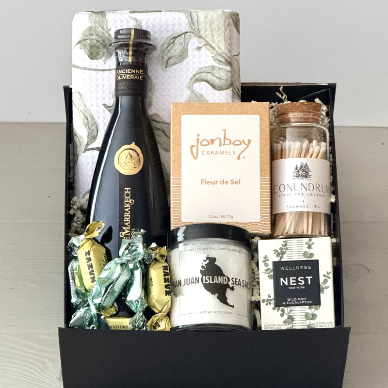 gift box including a kitchen towel, olive oil, caramel, wooden matches, candle, sea salt, chocolate, in a luxury gift box
