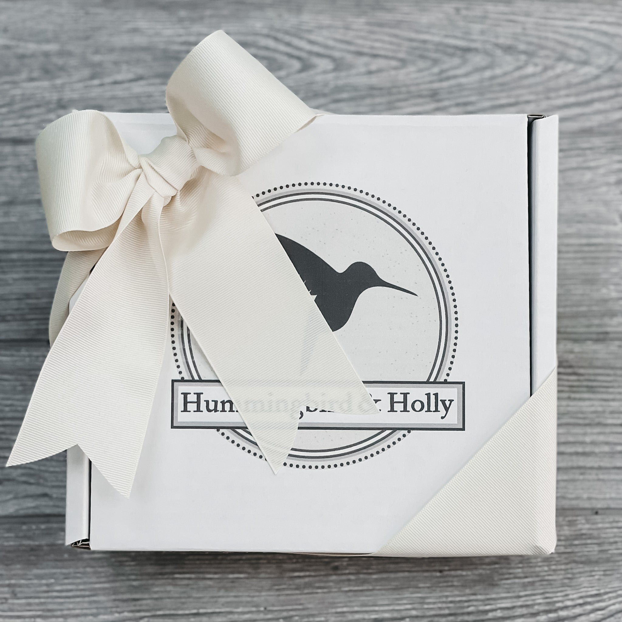 closeup of 8 inch by 8 inch gift box with Hummingbird and Holly logo