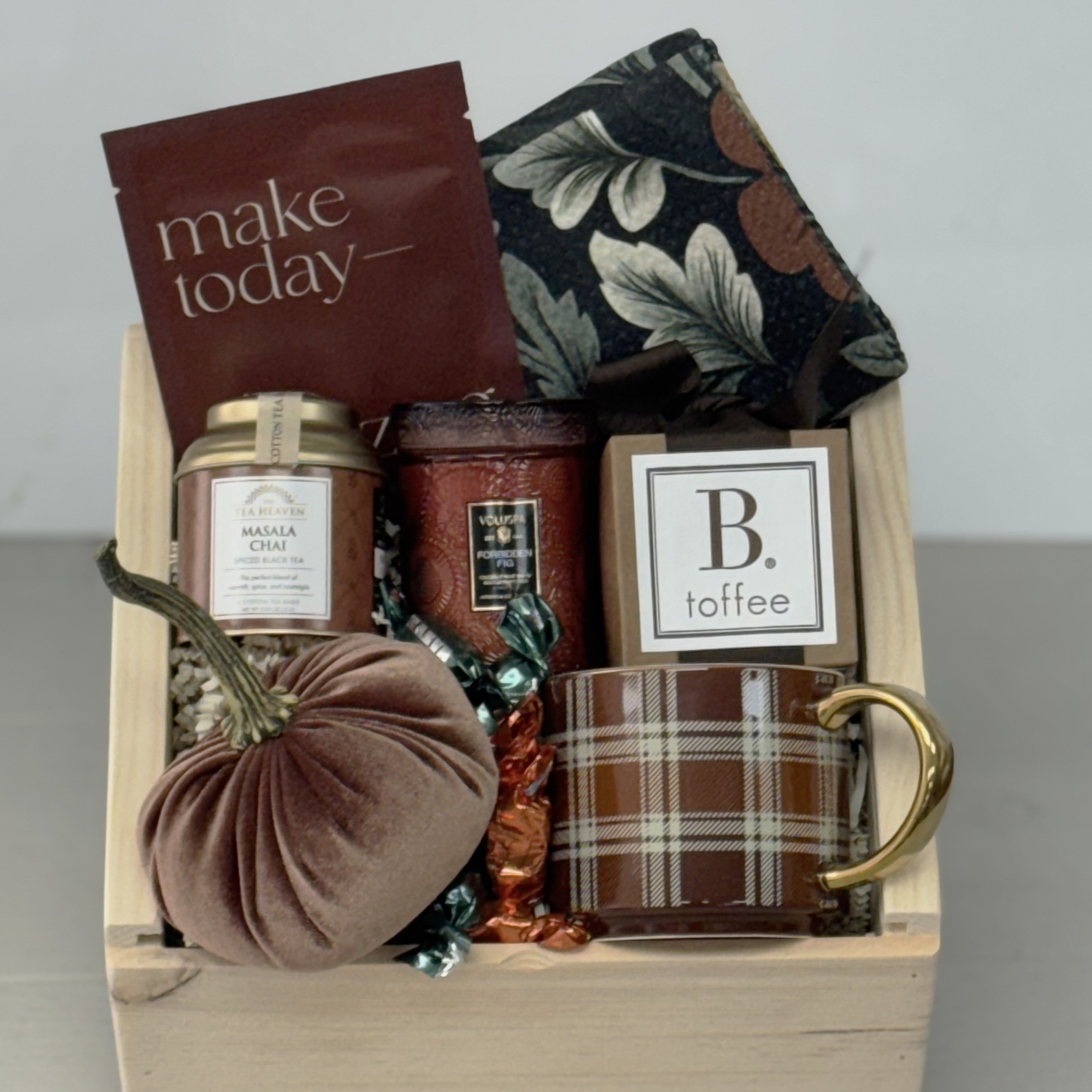 Gift basket with candles, a mug, and other items on a neutral background