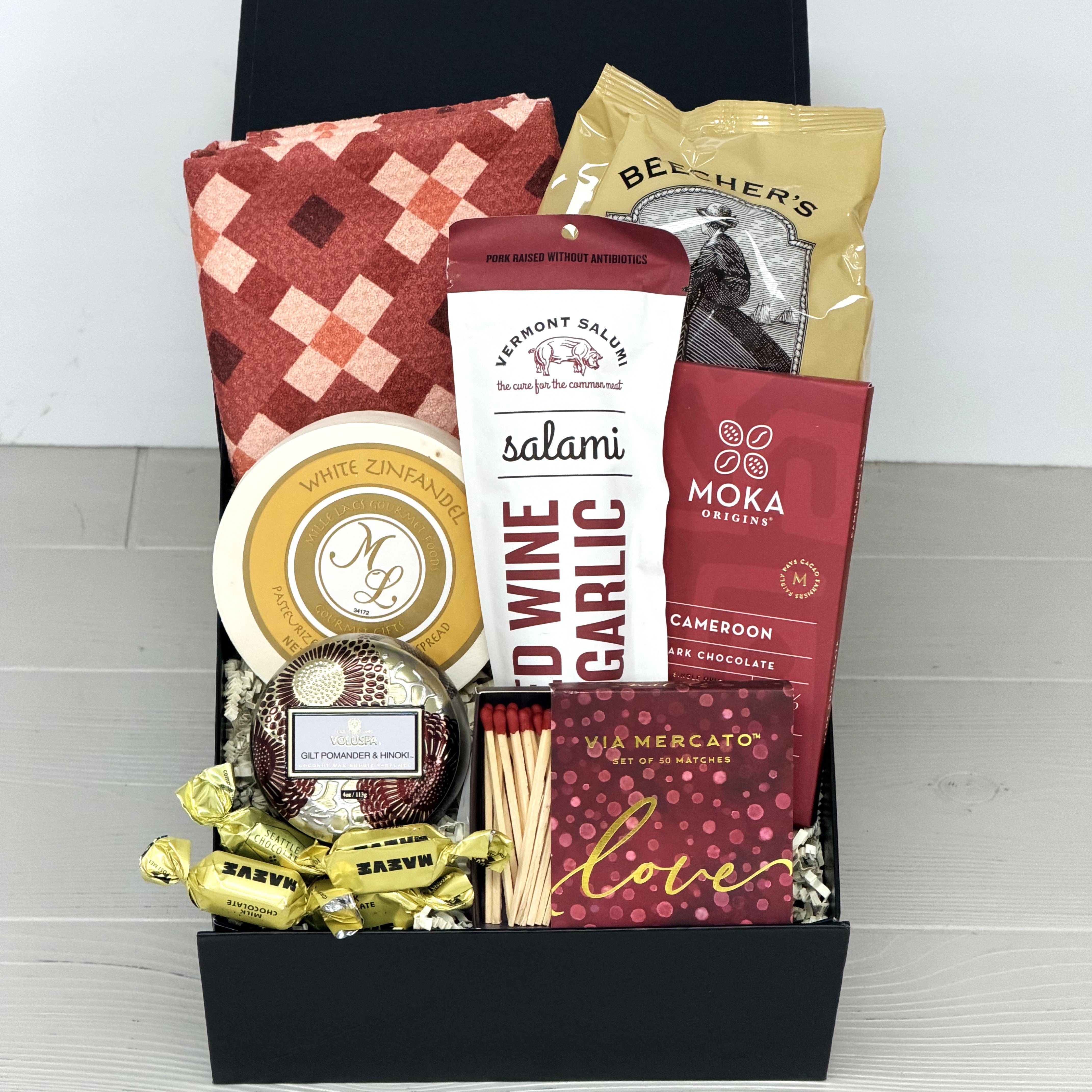 Gift basket with various items including chocolate, salami, and candy on a white background