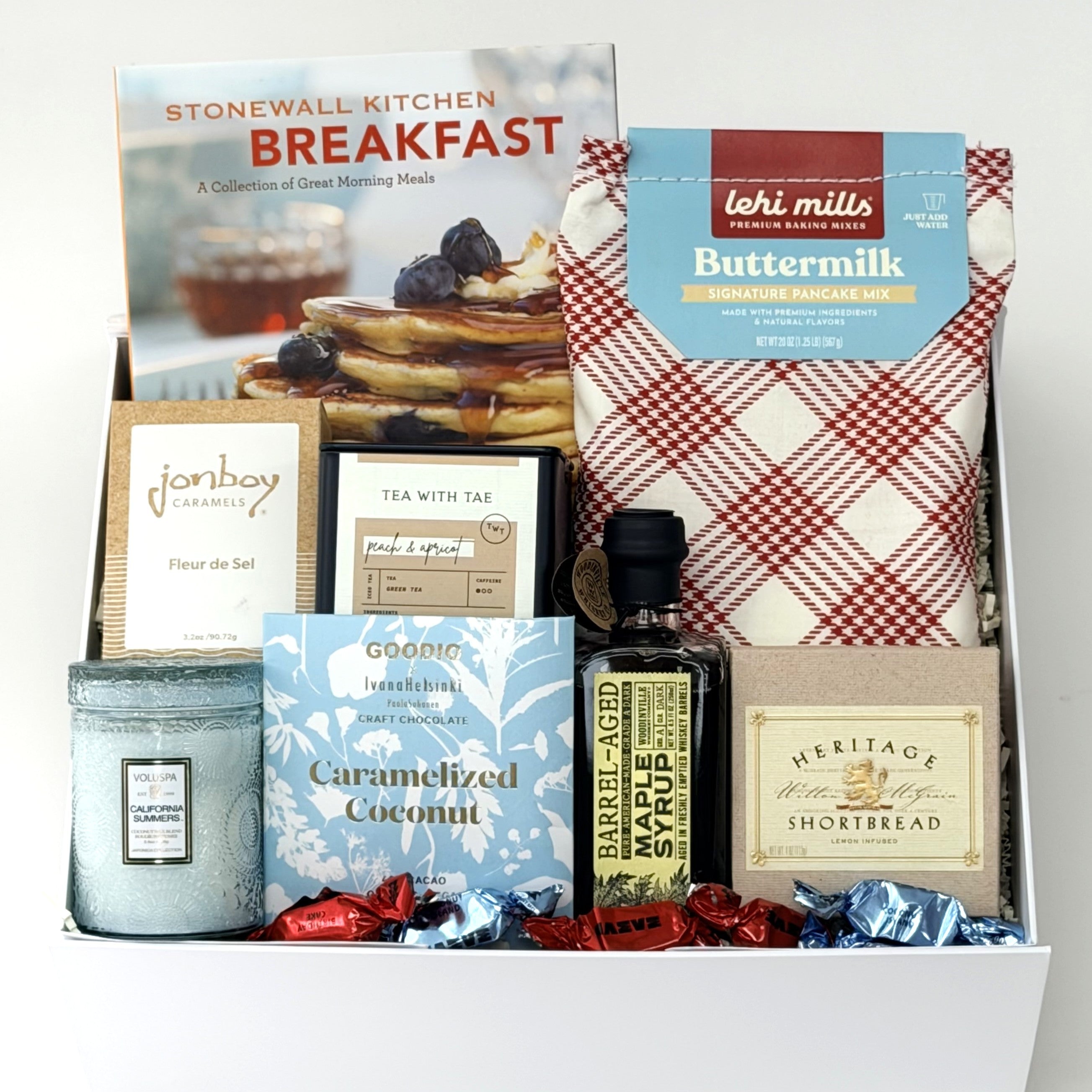 Gift basket with pancake mix, candles, and other items on a white background