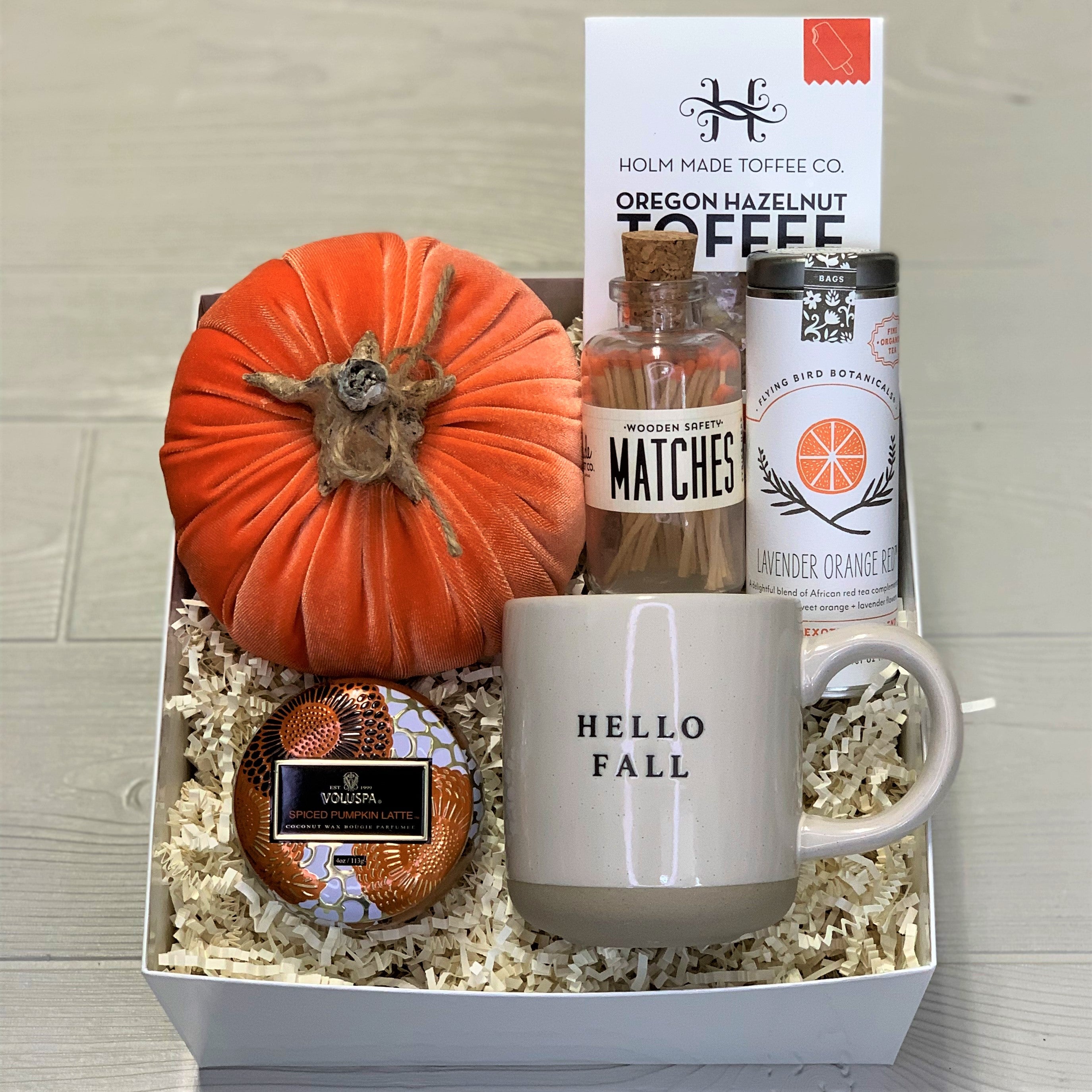 Fall gift basket includes a velvet pumpkin, toffee, tea, wooden matches, a Voluspa scented candle, and a ceramic mug