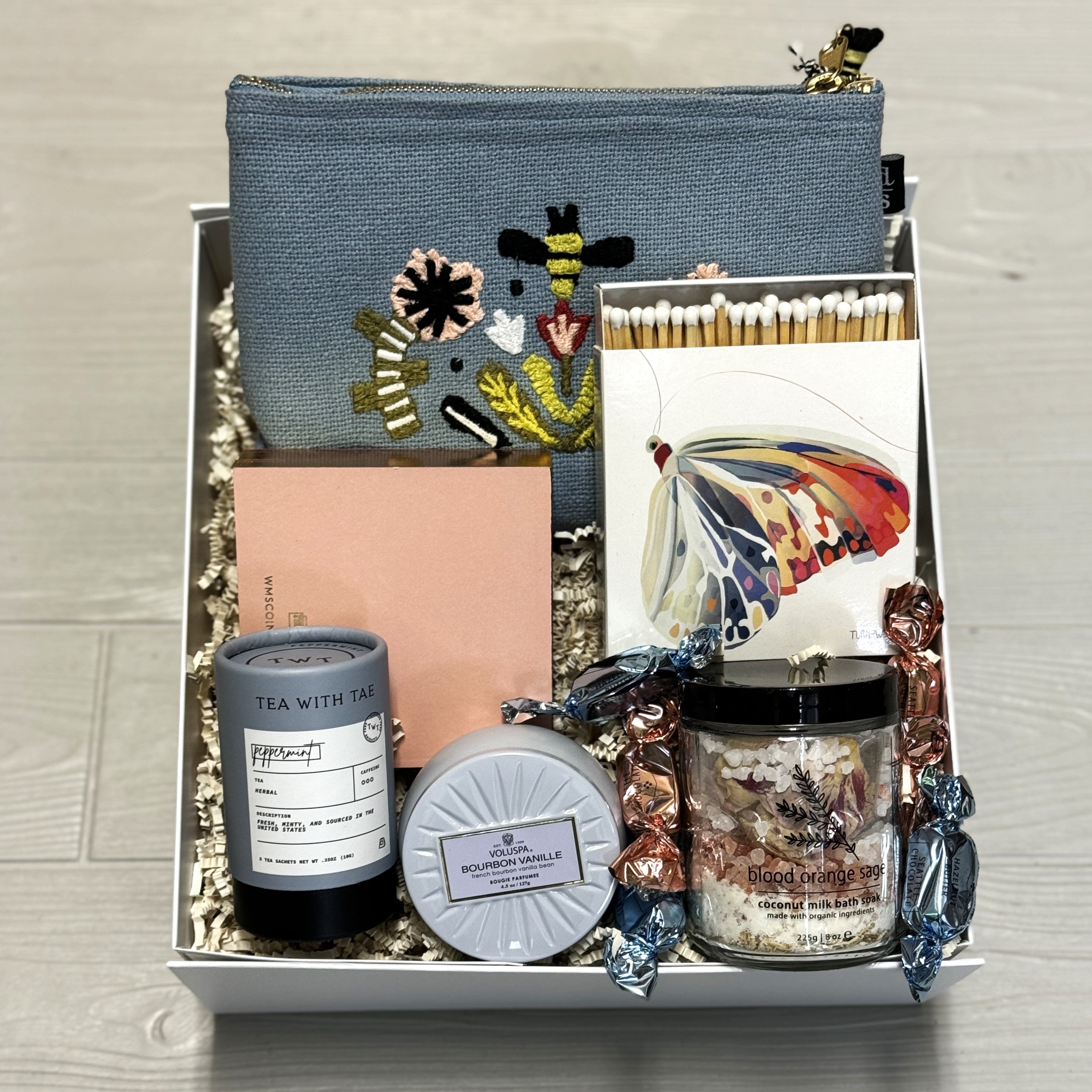 gift for administrative assistant includes a makeup bag, notepad, matches, tea, candle, chocolate, bath salts