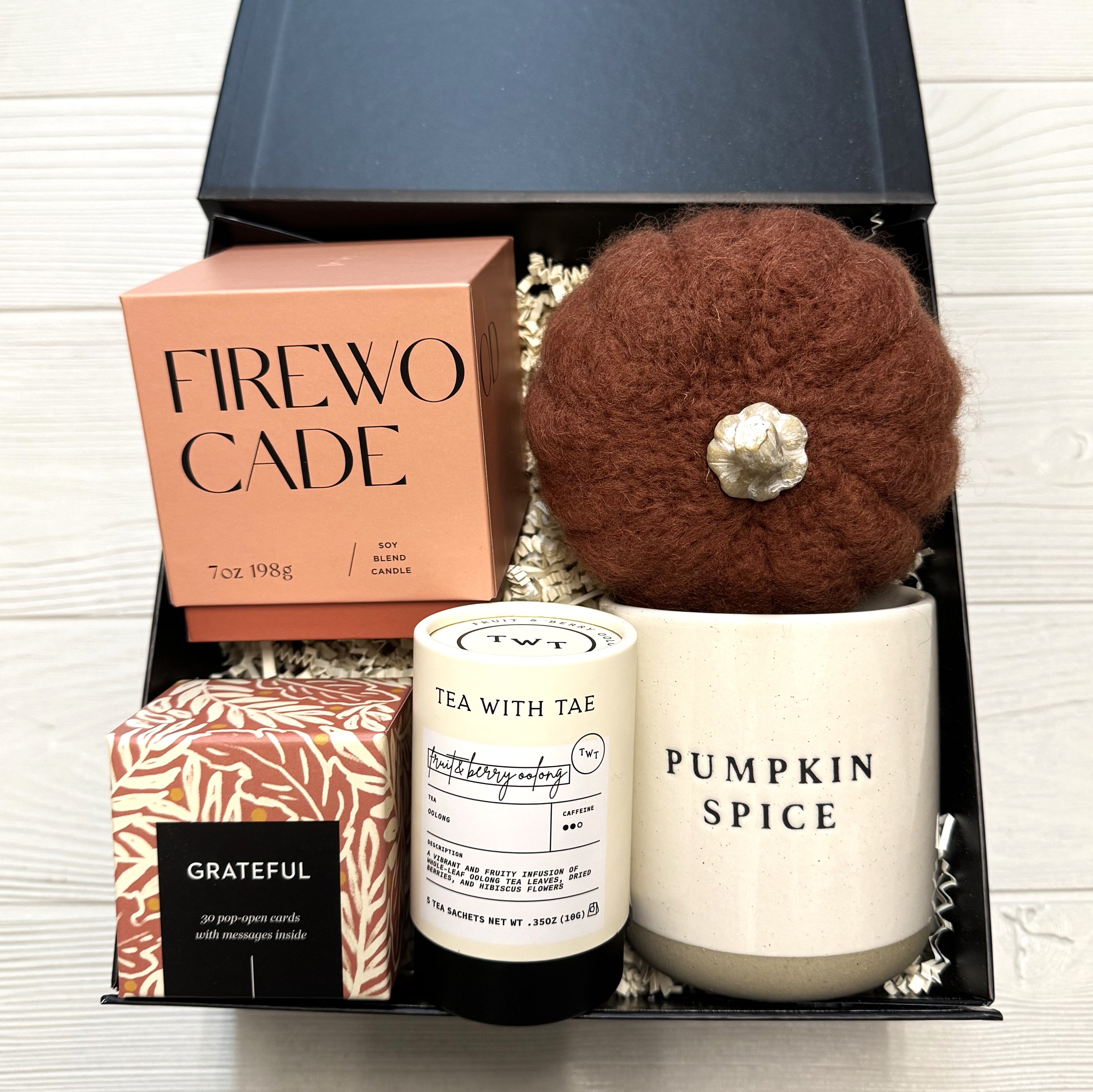 gift basket that includes a scented candle, mug, tea, felt pumpkin