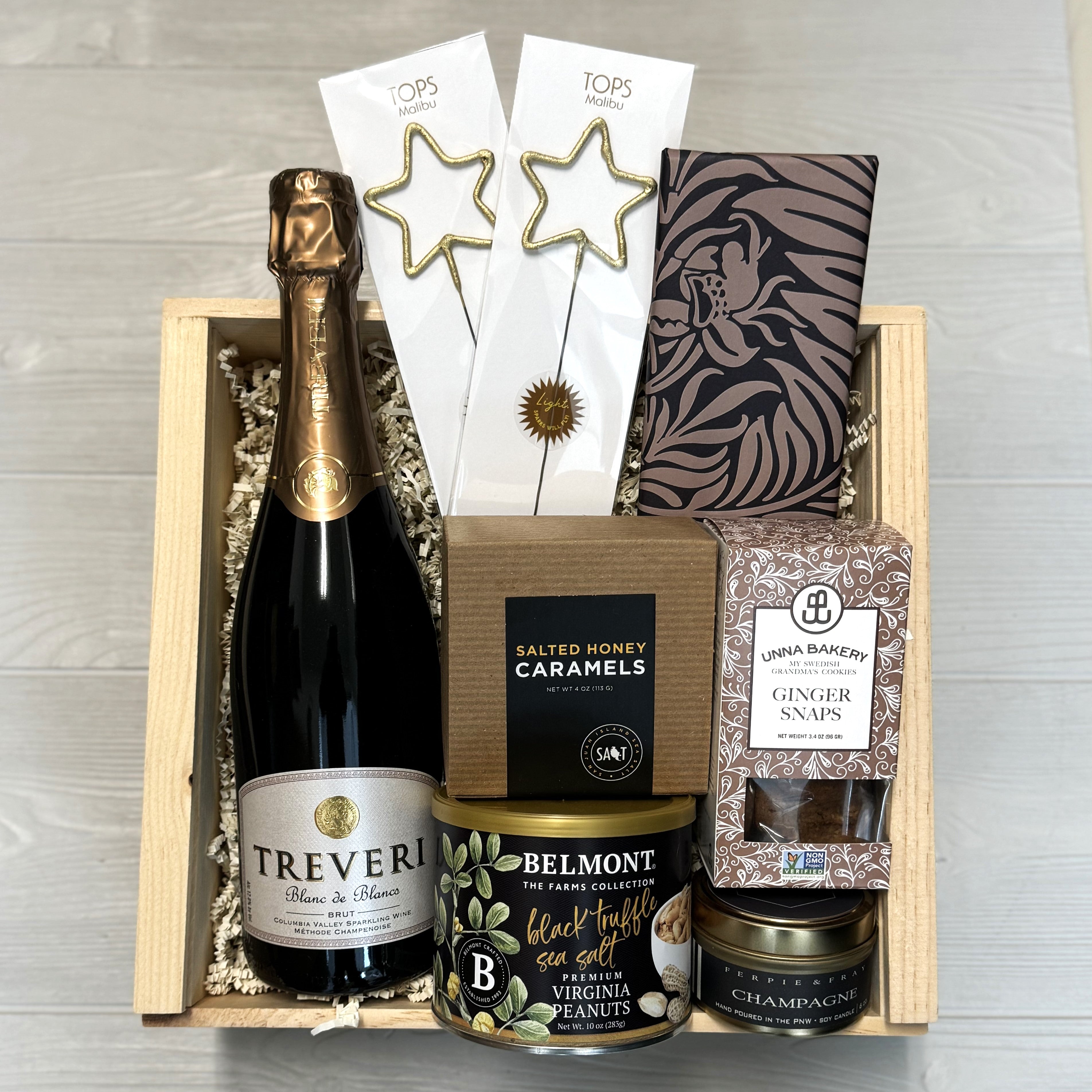 a gift basket containing treveri cellars champagne, sparklers, chocolate, cookies, caramel, nuts, and a candle