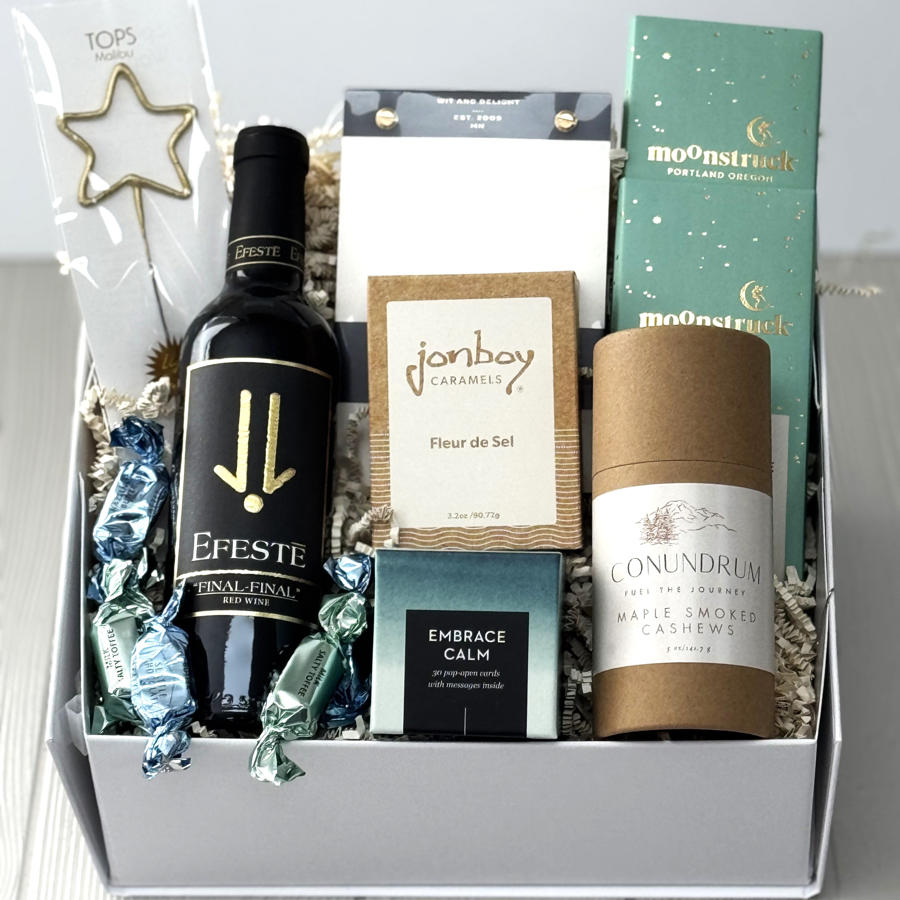this spring gift basket includes Efeste Final Final red wine, a star-shaped sparkler by Tops malibu, notepad, caramel, chocolate, cashews, boxed quotes 