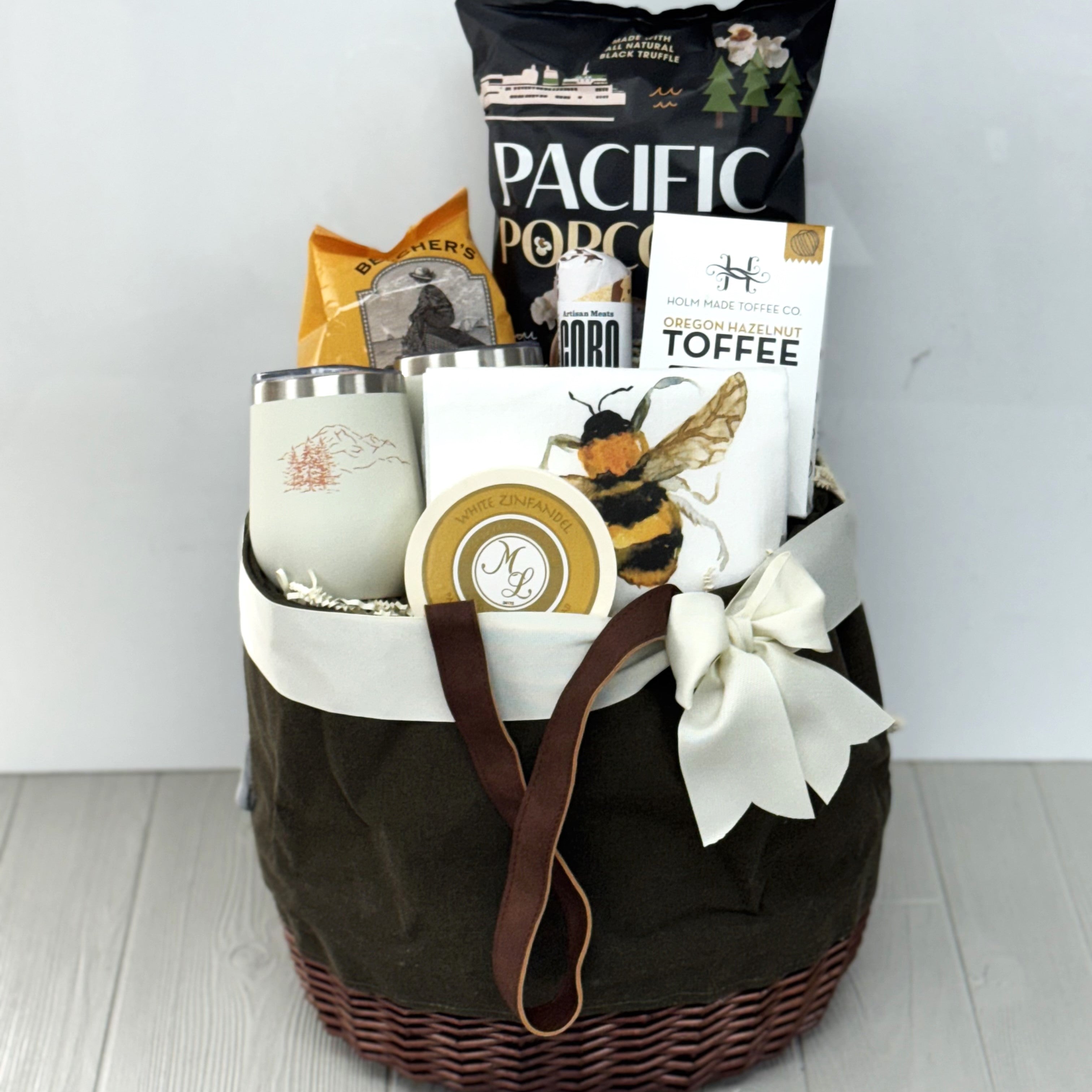picnic basket gift containing popcorn, crackers, salami, toffee, tumblers, kitchen towel, cheese spread