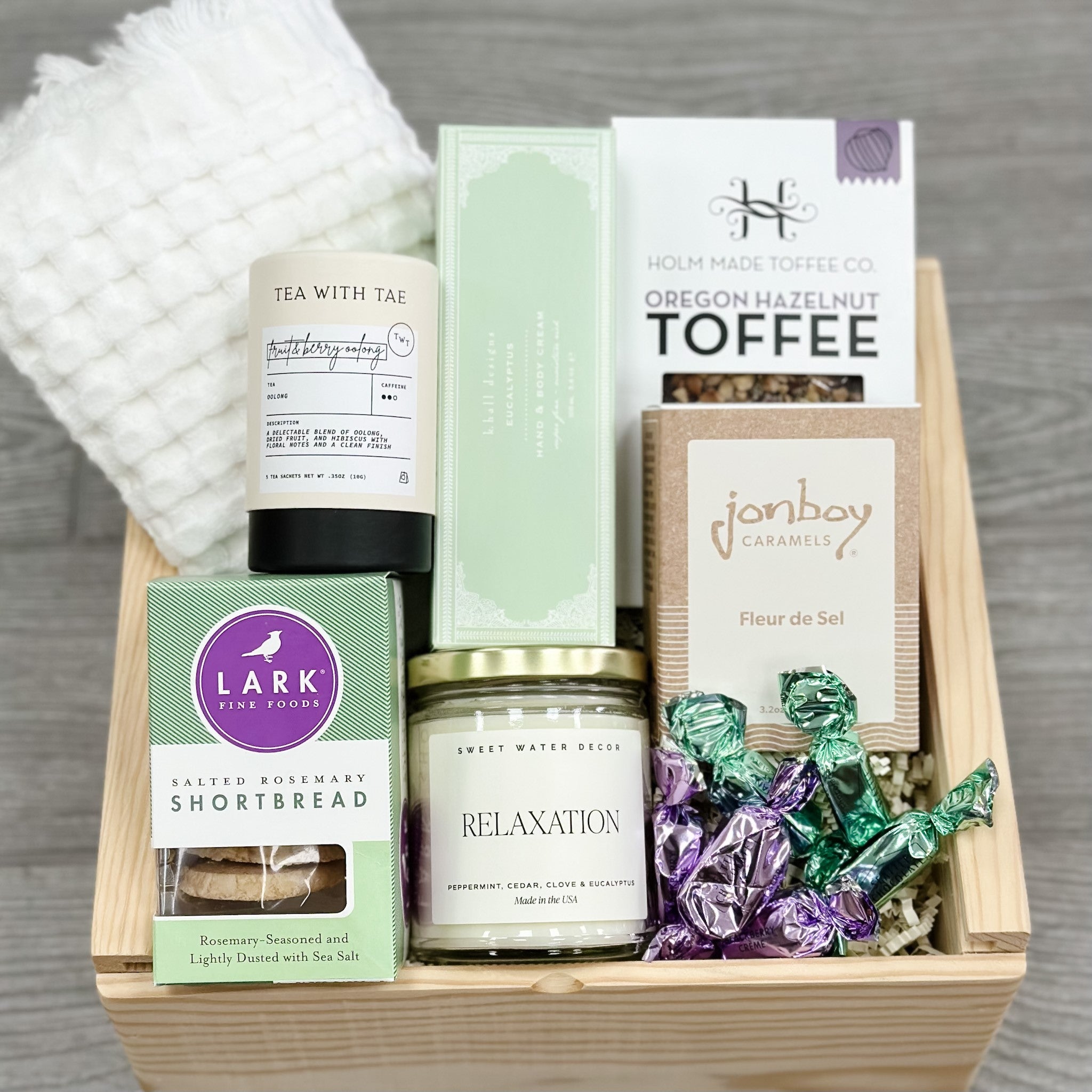 hand towel, tea, cookies, hand cream, toffee, caramel, candle, cookies, chocolate all packaged in our lavender and rosemary gift basket