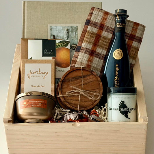 Cookbook, dish towel, olive oil, sea salt, coasters, candle, chocolate all packaged in a wooden slide lid box.