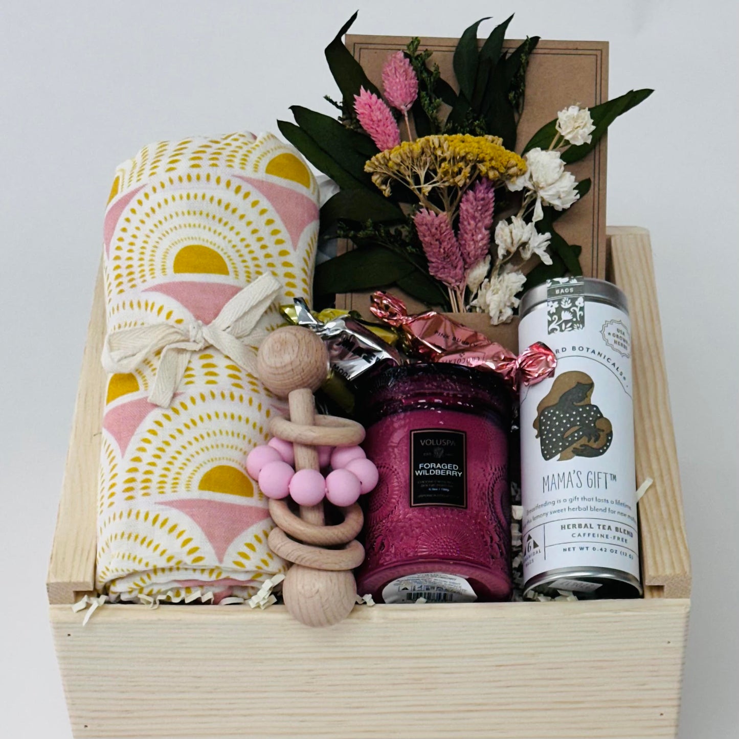 bamboo swaddle, wooden rattle, candle, tea, chocolate, dry flowers packaged in our 9x9 wooden slide lid box.