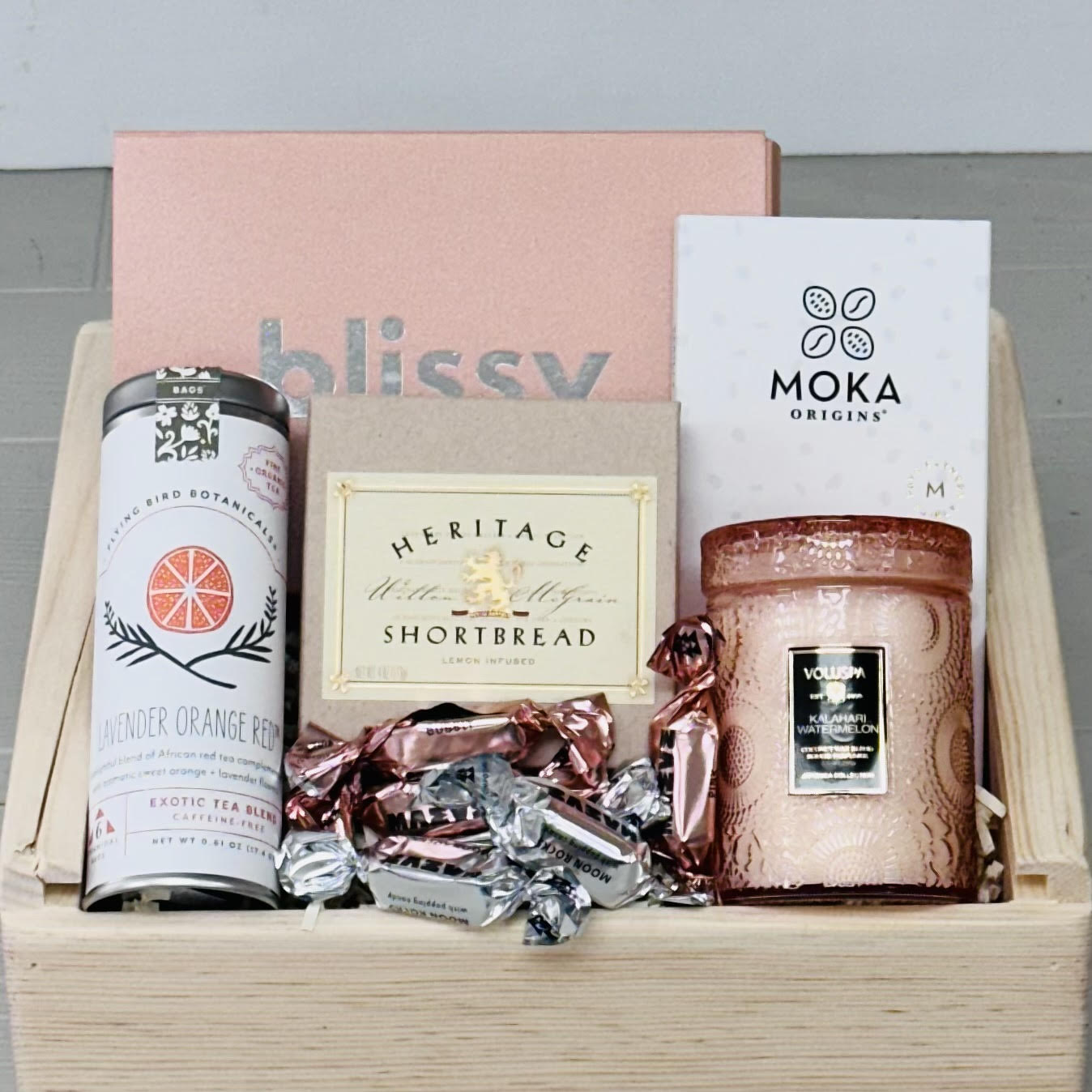 Gift box with a silk sleep mask, tea, shortbread, candle,  and chocolate.