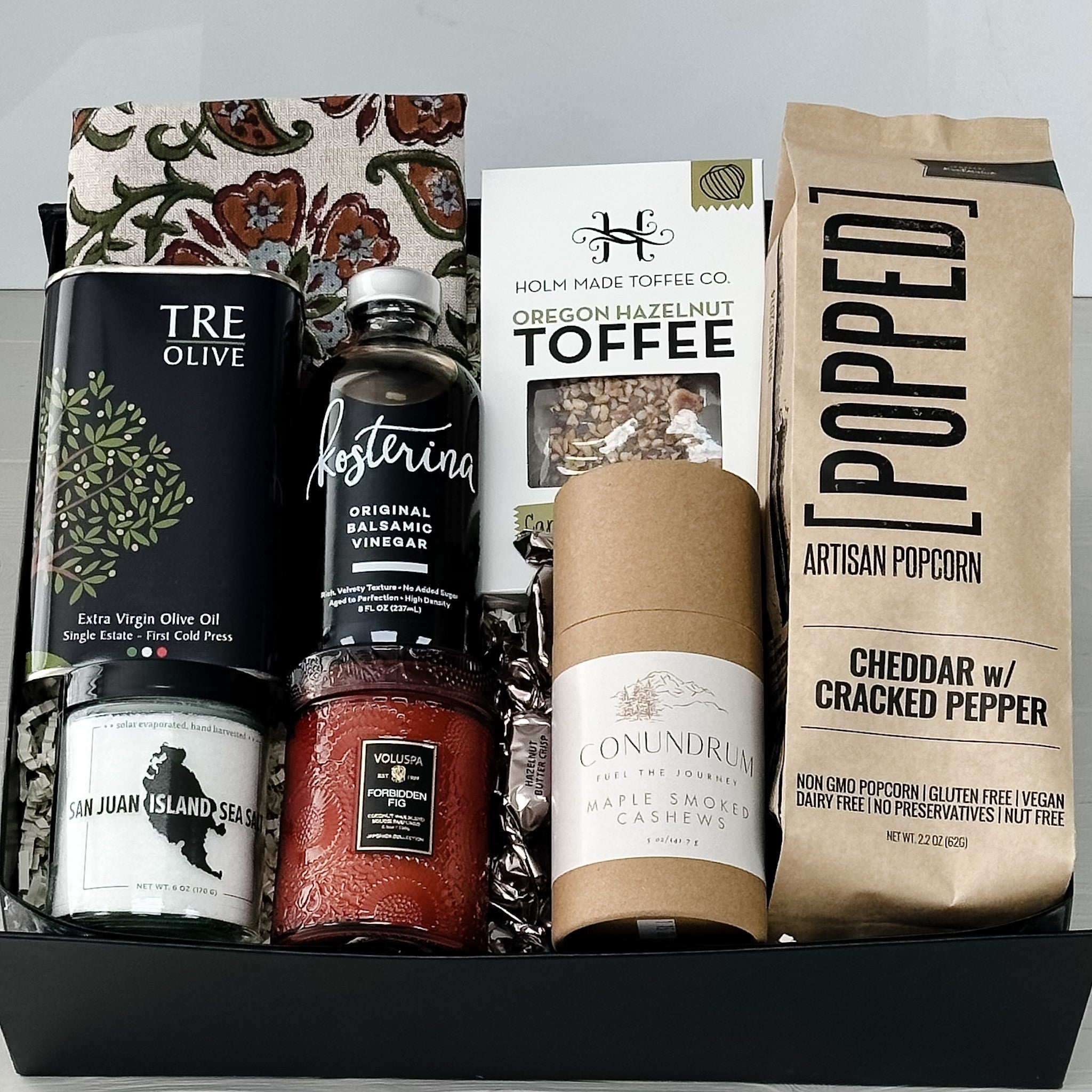 Gourmet gift basket with olive oil, balsamic vinegar, toffee, popcorn, and other items.