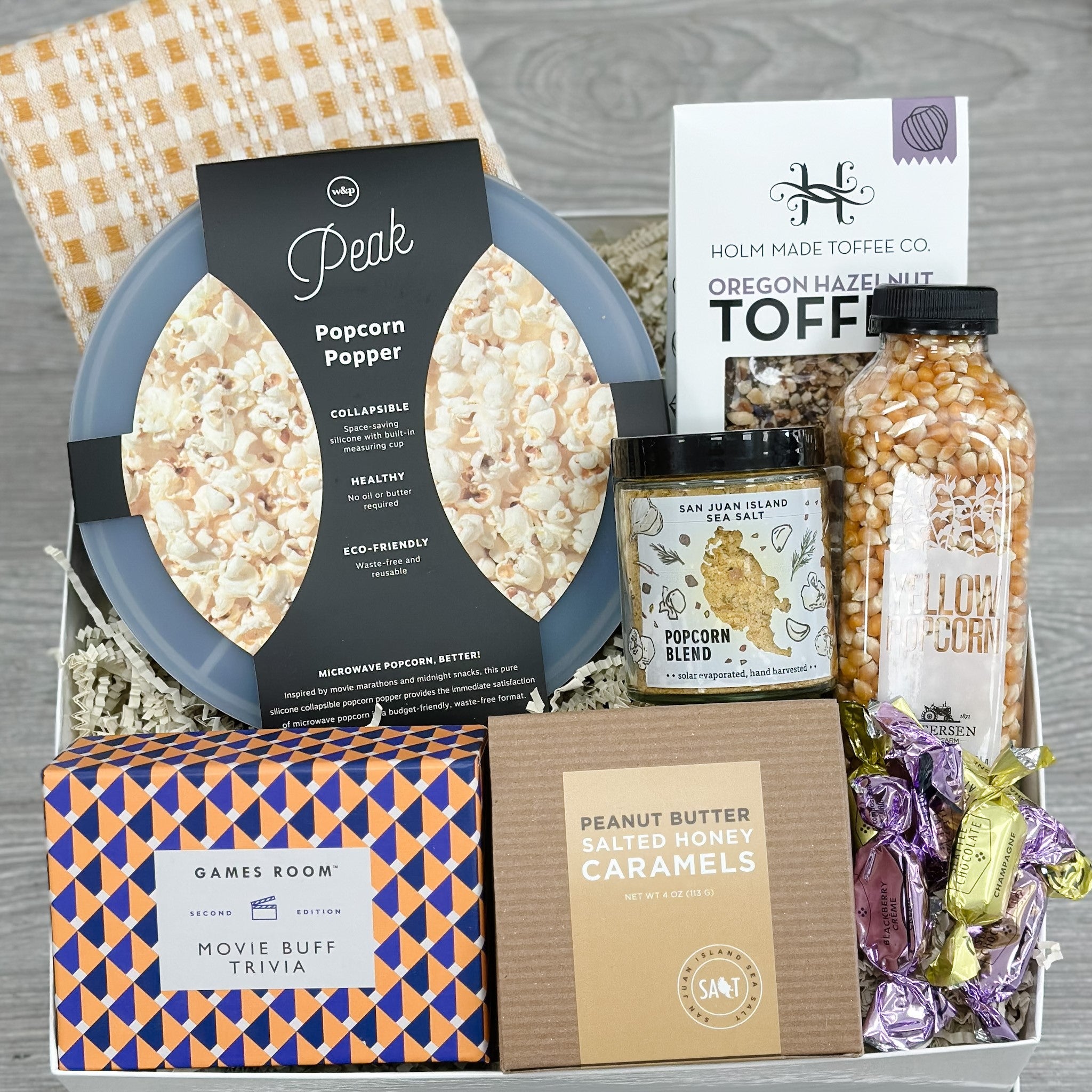 popcorn popper, popcorn kernels, popcorn seasoning salt, toffee, caramel, game, chocolate, dish towel all included in our movie night gift basket