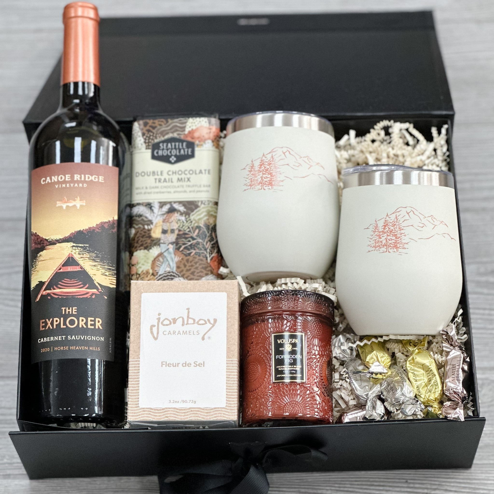 red wine, wine tumblers, chocolate, caramel, scented candle, sprinkle of truffles all packaged in our autumnal happy hour gift basket.