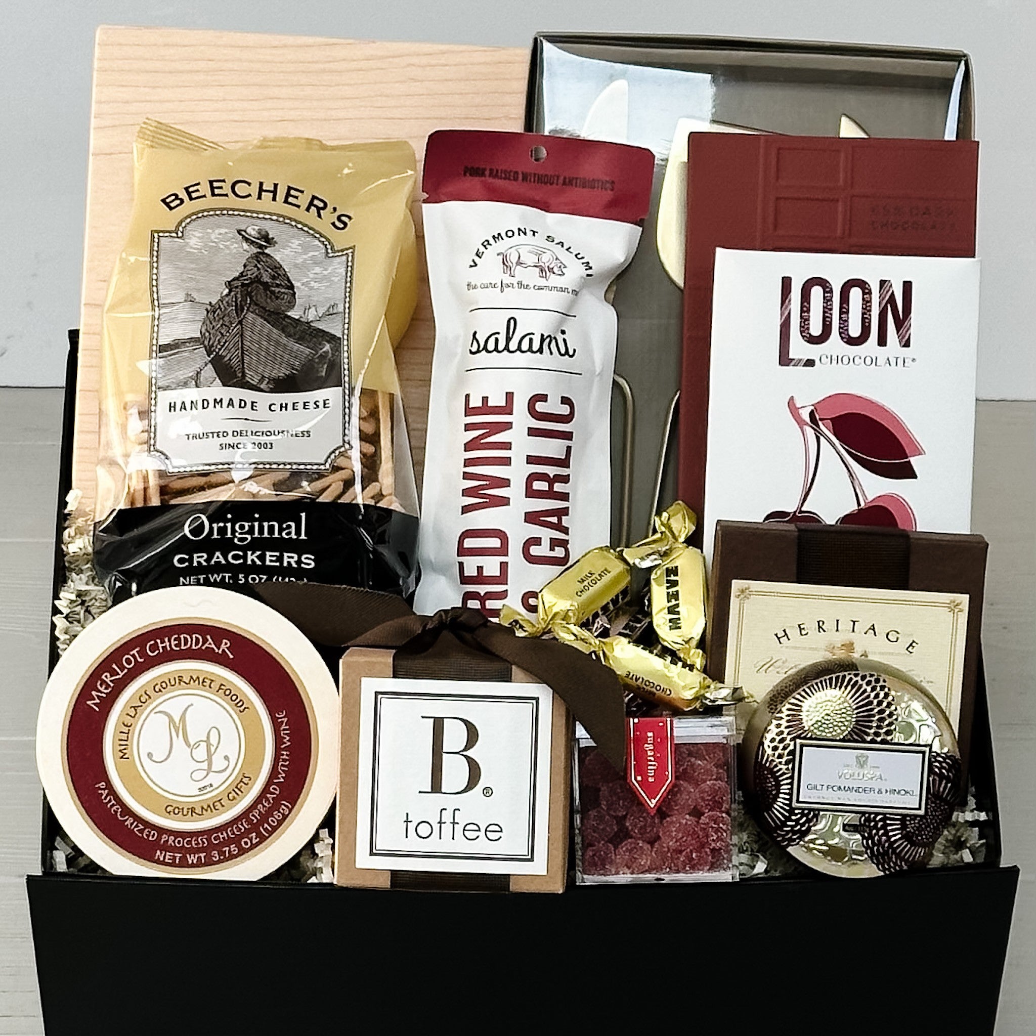 cheese board, knives, crackers, cheese, salami, chocolate, toffee, shortbread, candy, candle all included in our large holiday charcuterie gift basket