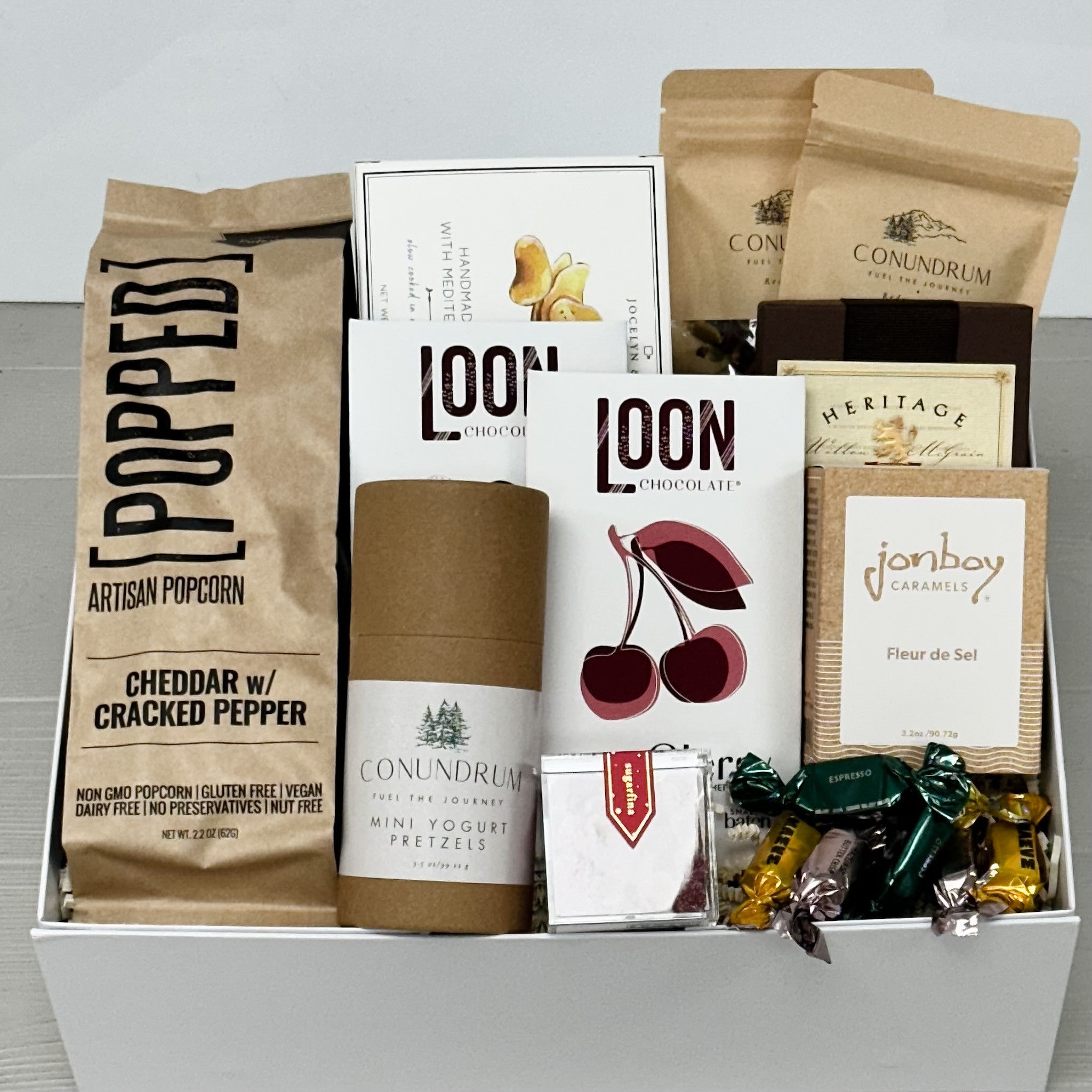 popcorn, potato chips, honey roasted almonds, maple smoked cashews, mini yogurt pretzels, chocolate bars, shortbread, caramel, candy, truffles all included in our medium winter treats gift basket.