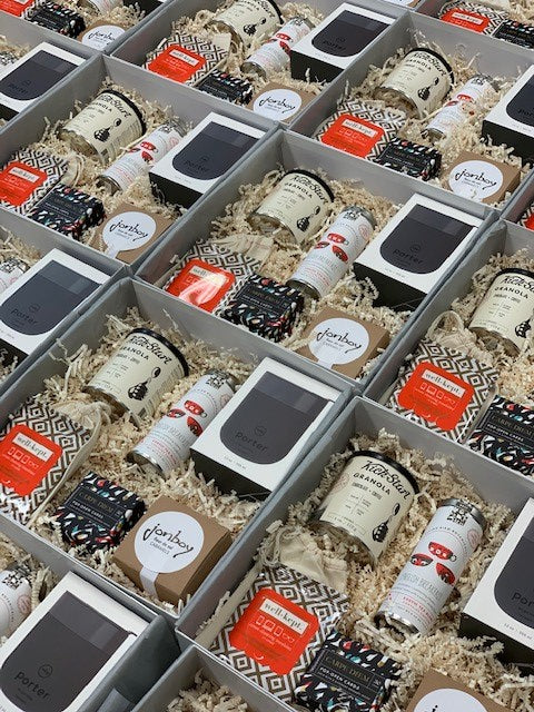 six corporate gift baskets that include mugs, caramel, screen-cleaning wipes, granola, inspirational quotes, and tea