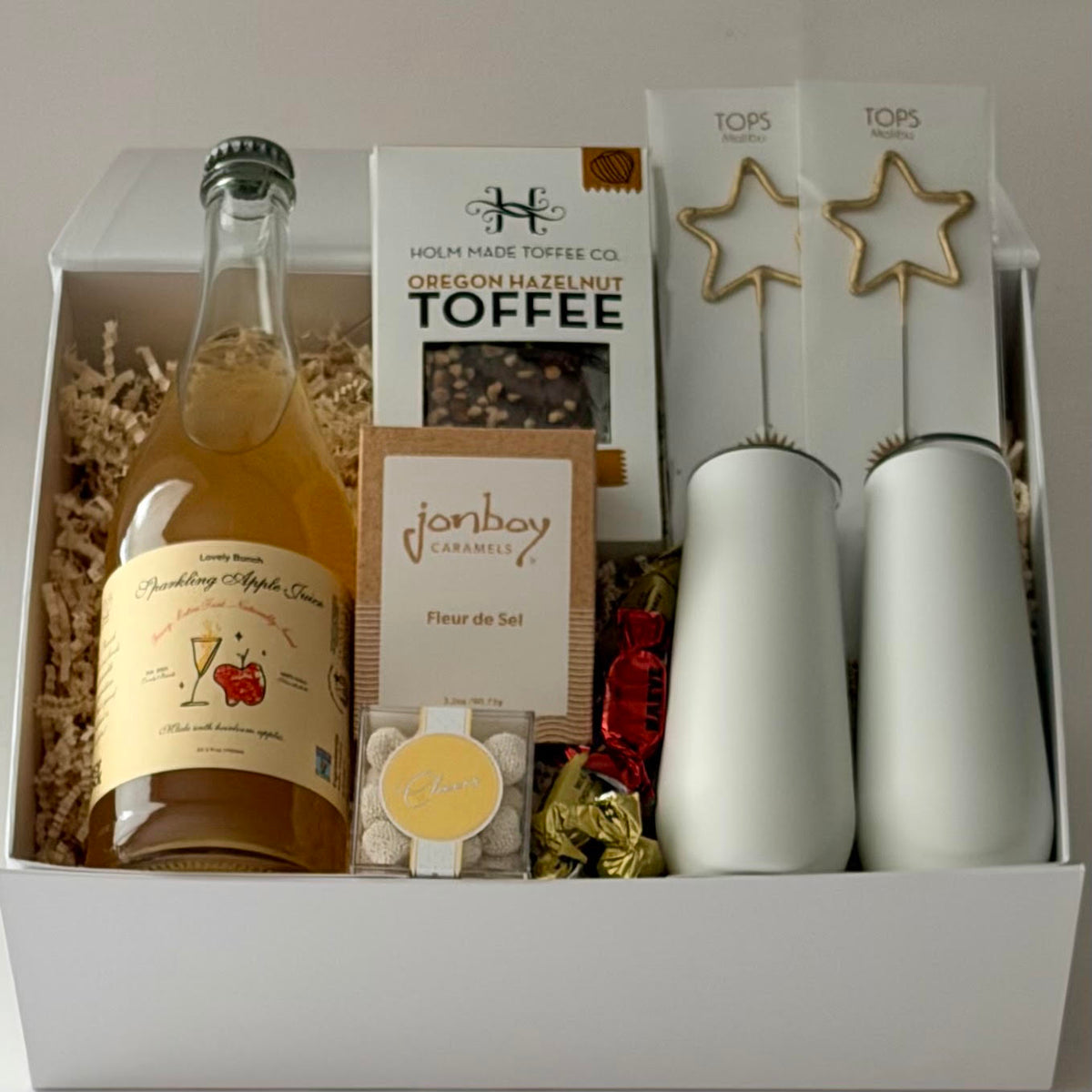 Gift box includes sparkling apple cider, toffee, caramel, candy, sparklers, 2 insulated stemless flutes, and bonbons. 