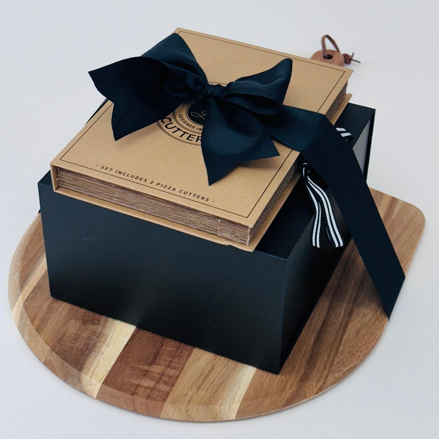 Close up of pizza peel with stack of black box and set of pizza knives.