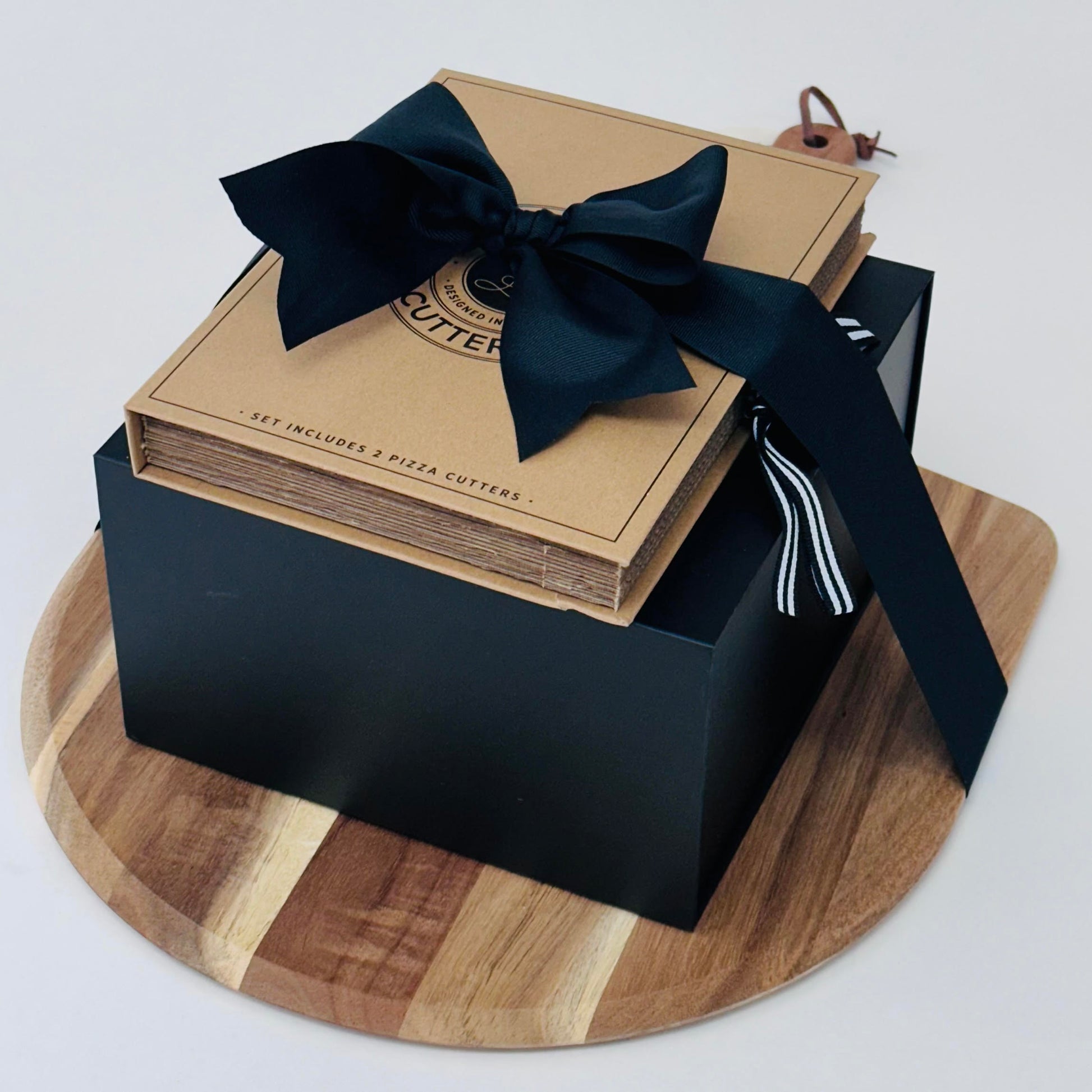Close up of pizza peel with stack of black box and set of pizza knives.