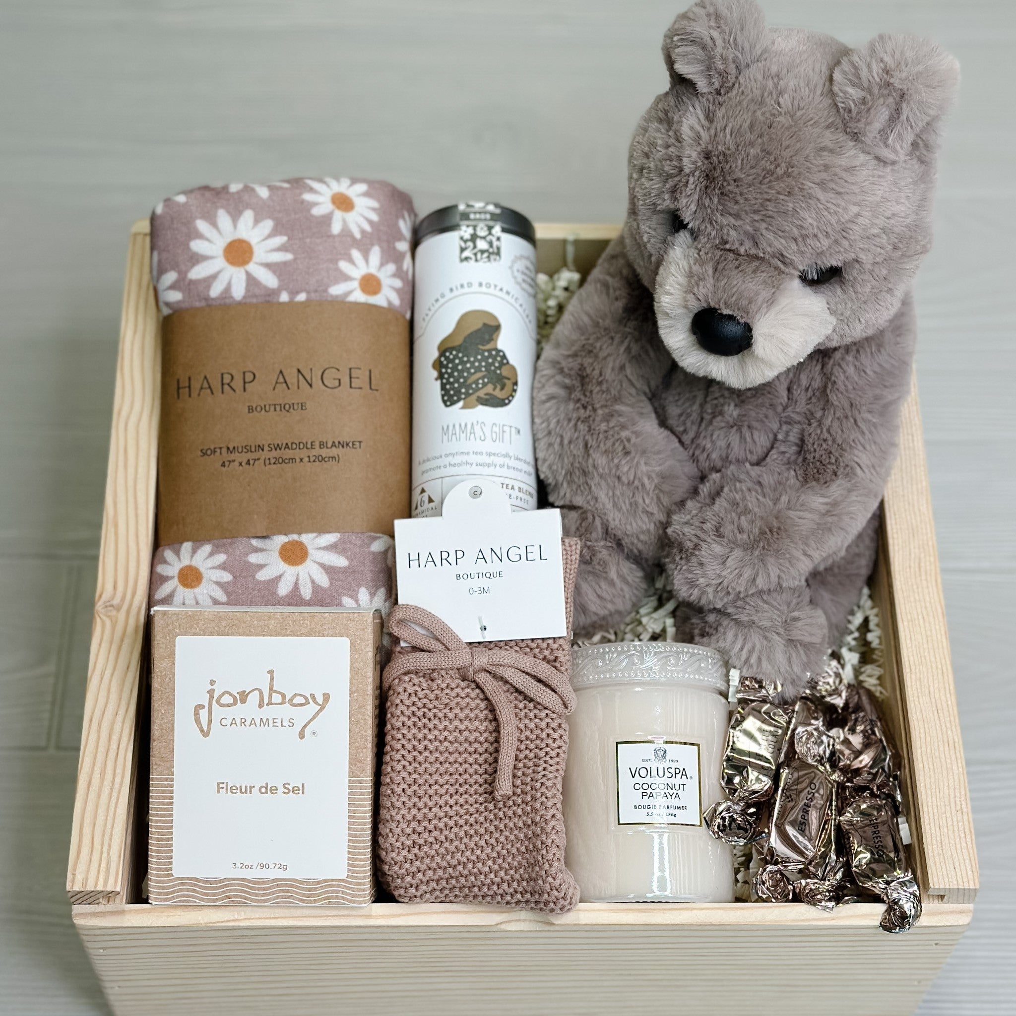 baby gift basket with teddy bear, swaddle, tea, caramel, knit booties, candle and truffles