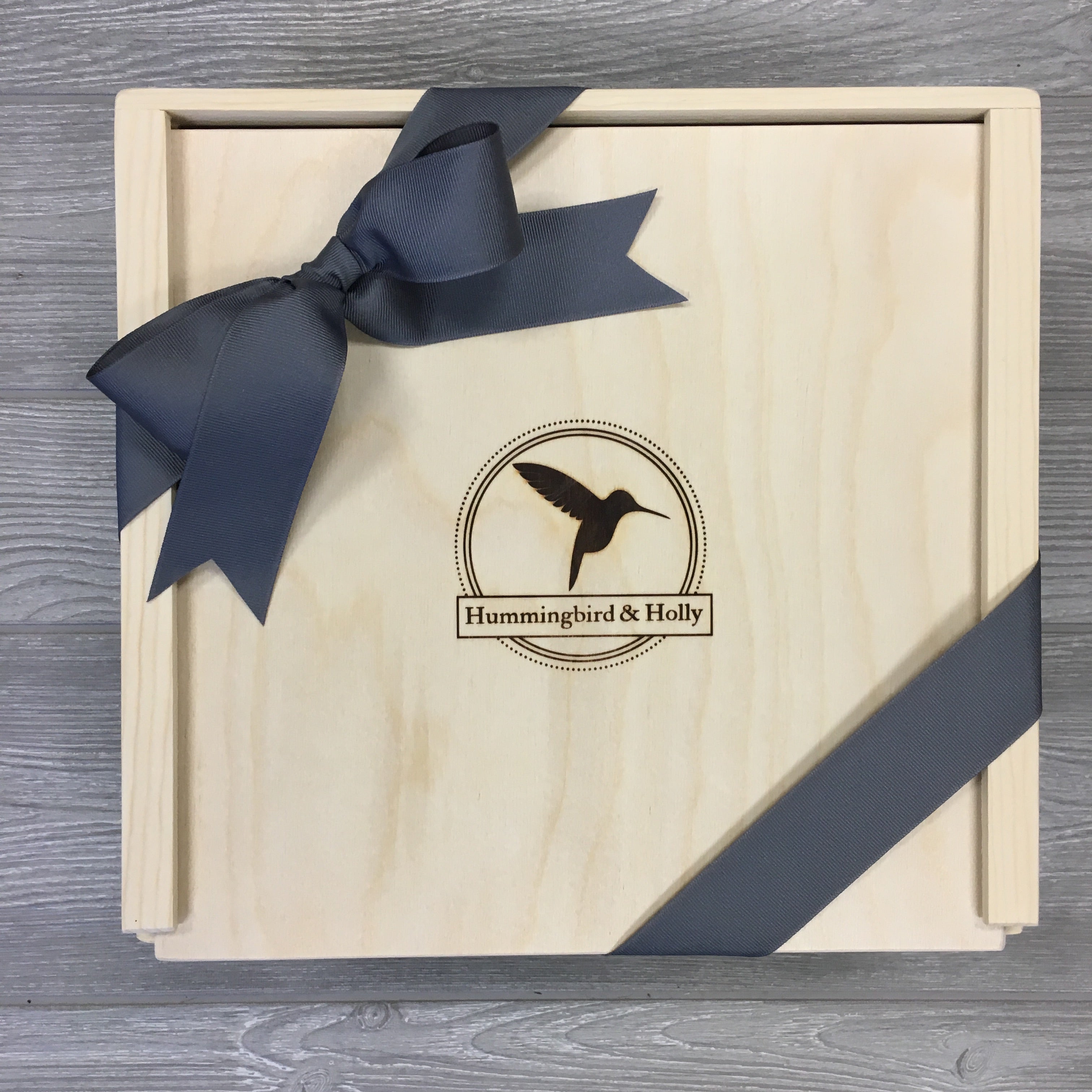 closeup of the wooden gift box with a Hummingbird and Holly logo included in the housewarming gift basket.