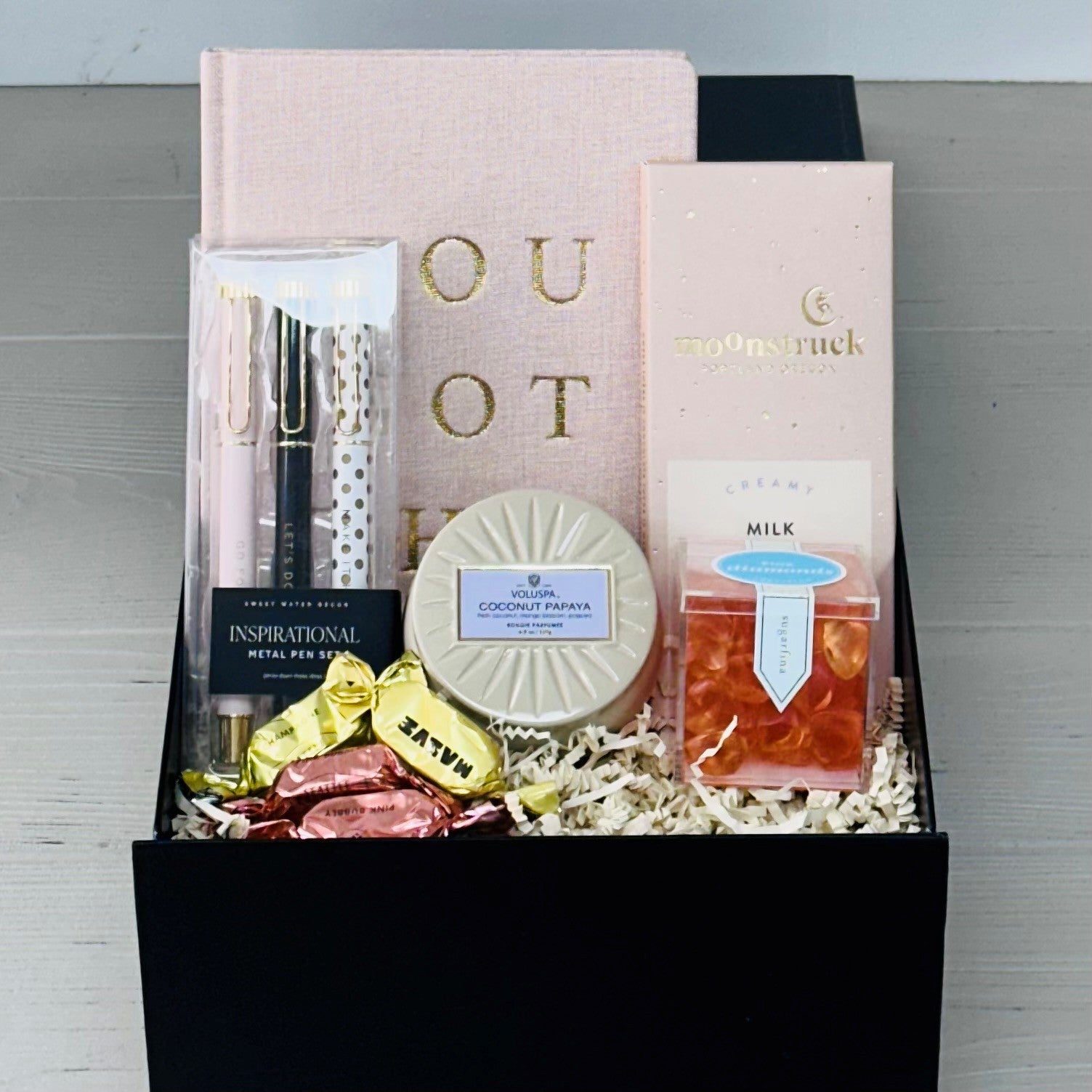 you got this gift box includes a notebook, set of pens, chocolate, candle, and sugarfina candy.